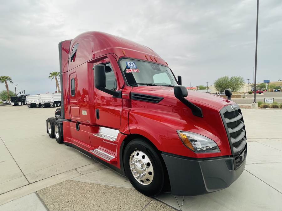Red 2023 Freightliner Cascadia, low miles, on the dealership lot